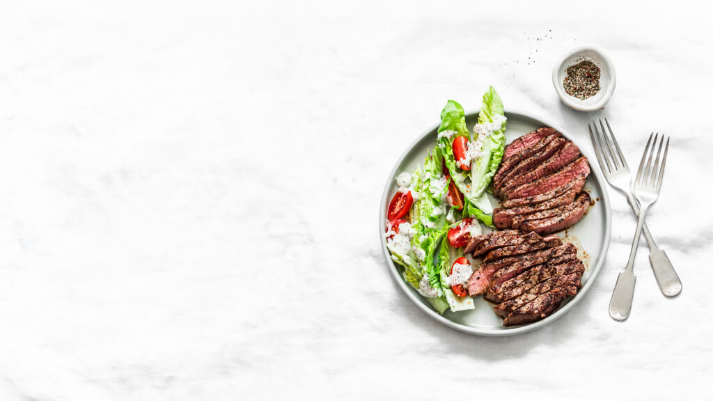 Medium rare beef steak and romaine cherry tomatoes yogurt dressing salad