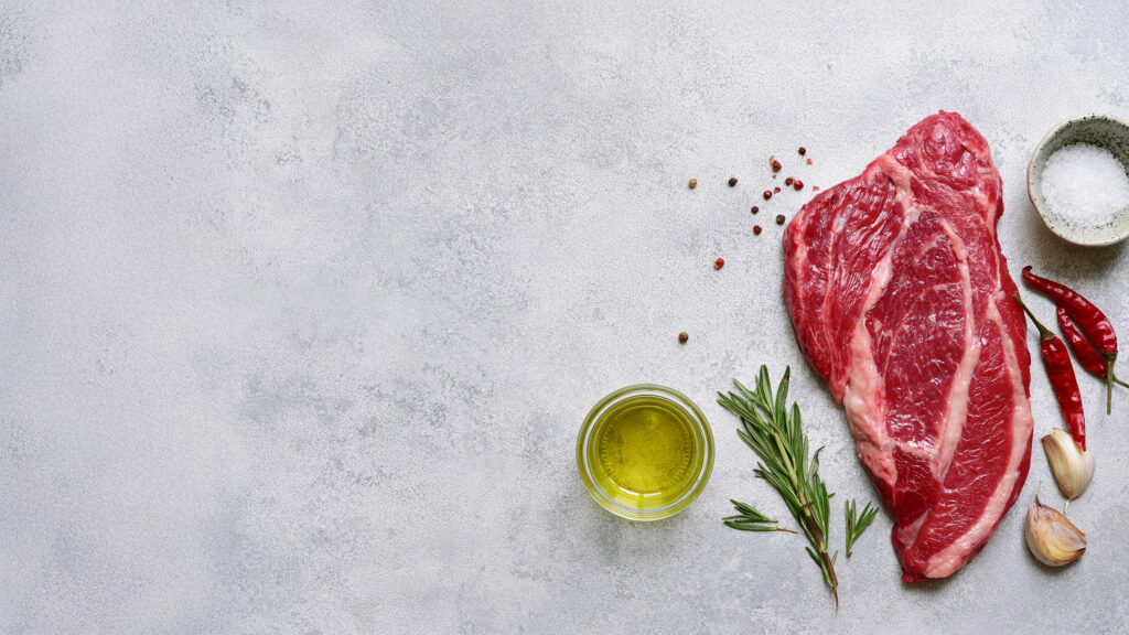 Raw organic marbled beef steak with ingredients for cooking